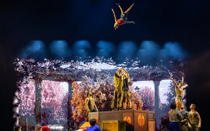 Acrobats performing mid-air flips during Cirque du Soleil Alizé stage show.