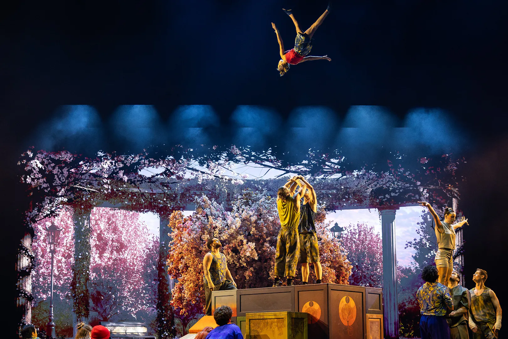 Acrobats performing mid-air flips during Cirque du Soleil Alizé stage show.