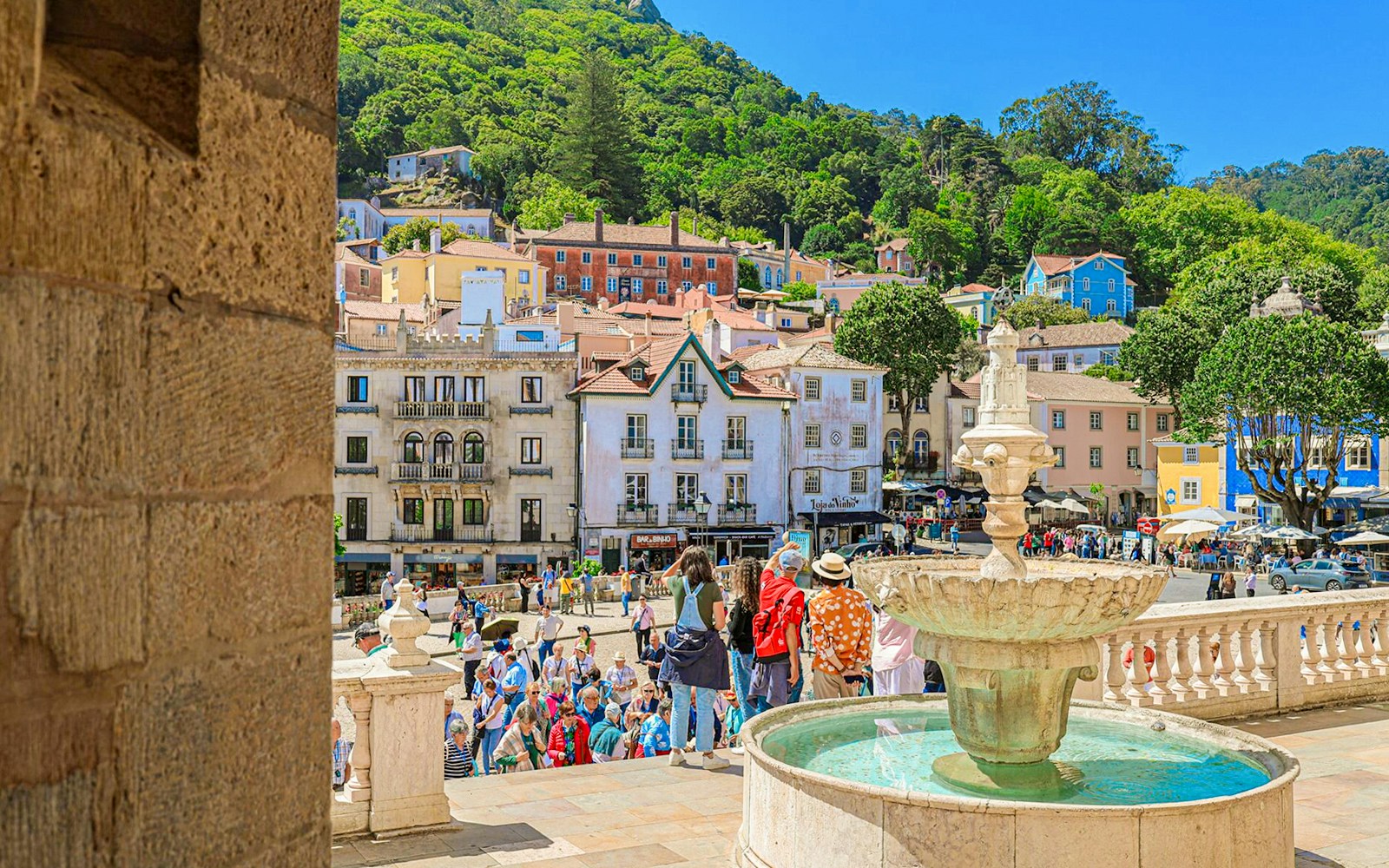 Sintra city square with a fountain, colorful buildings, and tourists exploring the area.