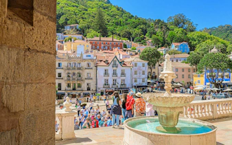 Sintra city square with a fountain, colorful buildings, and tourists exploring the area.