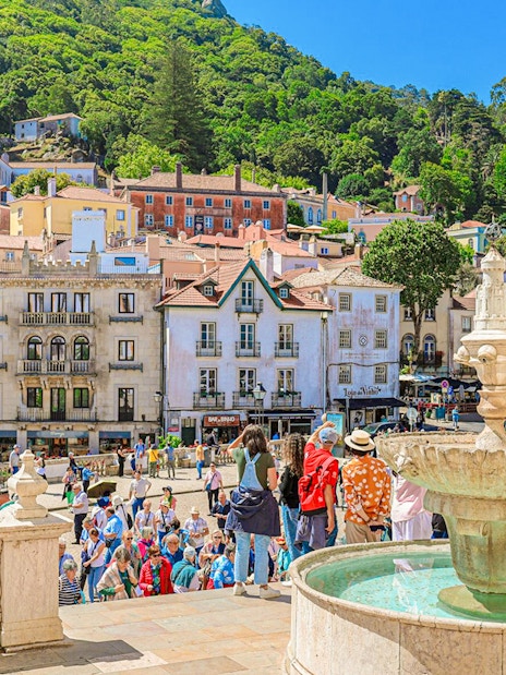 Sintra city square with a fountain, colorful buildings, and tourists exploring the area.