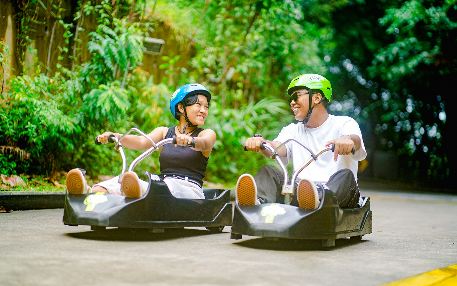 Couple enjoying Skyline Luge ride in Singapore amidst lush greenery.