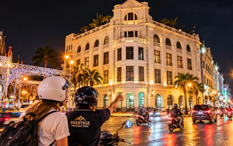 Motorbike tour in Medan passing London Sumatra building at night.