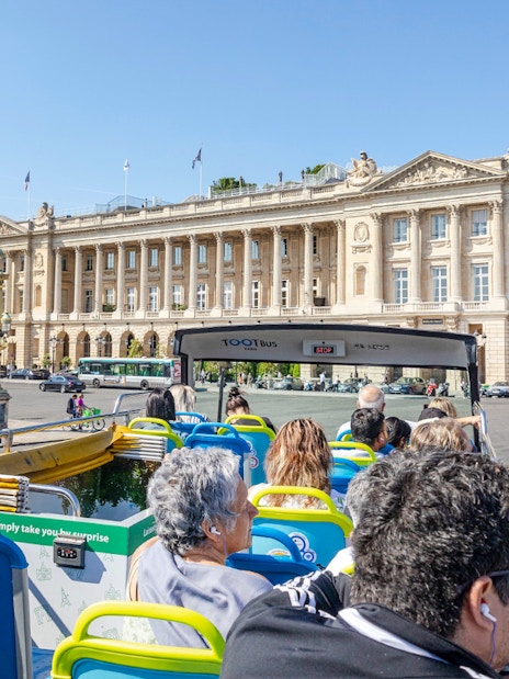 Tootbus tour passing Place de la Concorde in Paris, with passengers enjoying city views.