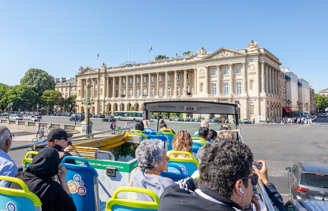 Tootbus tour passing Place de la Concorde in Paris, with passengers enjoying city views.