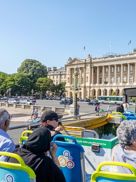 Tootbus tour passing Place de la Concorde in Paris, with passengers enjoying city views.