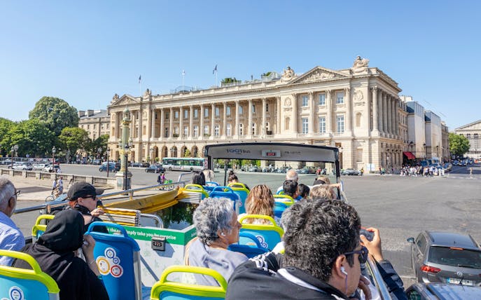 Tootbus tour passing Place de la Concorde in Paris, with passengers enjoying city views.