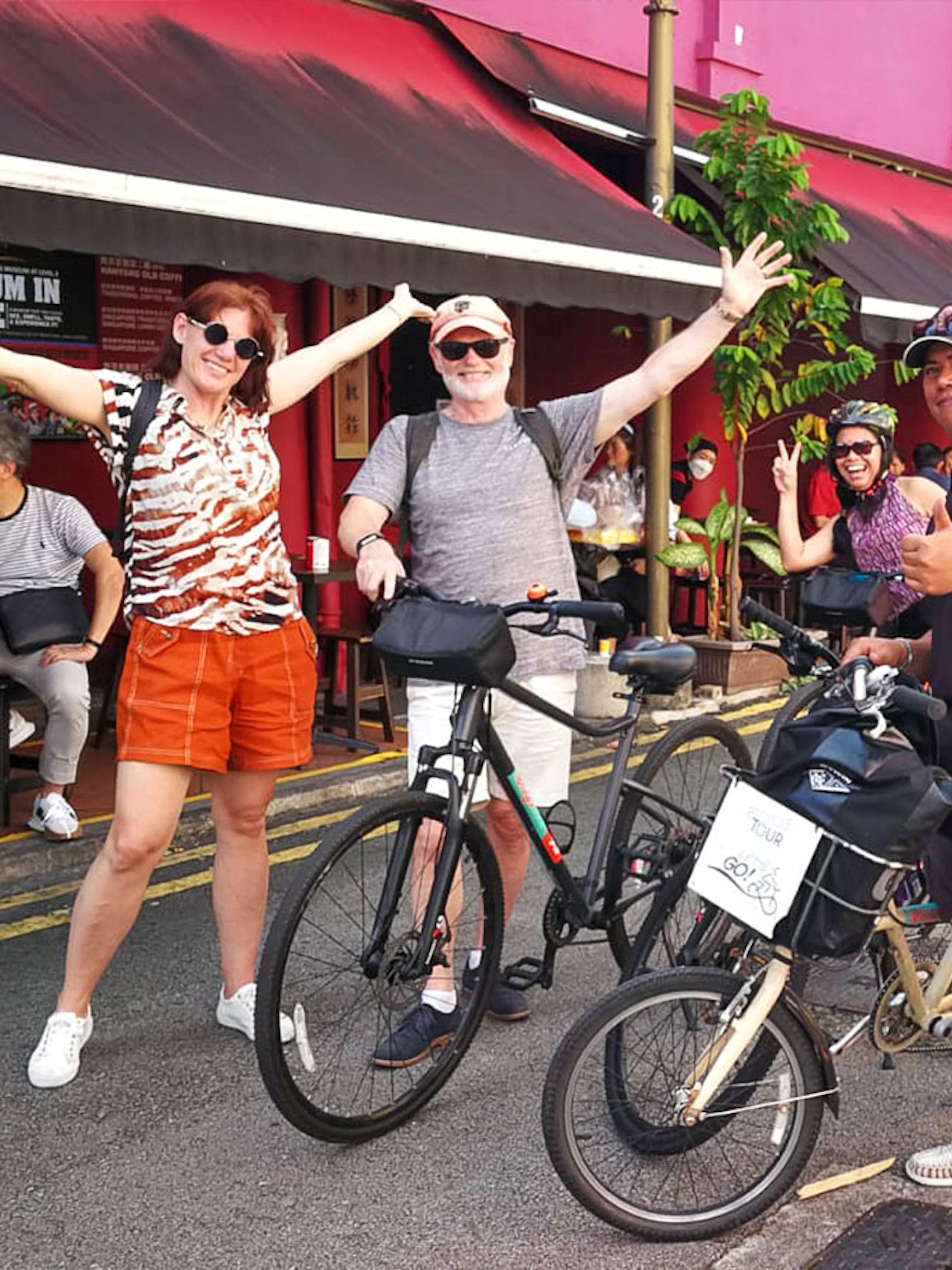 Group of cyclists enjoying a food tour in Singapore, stopping outside a cafe.