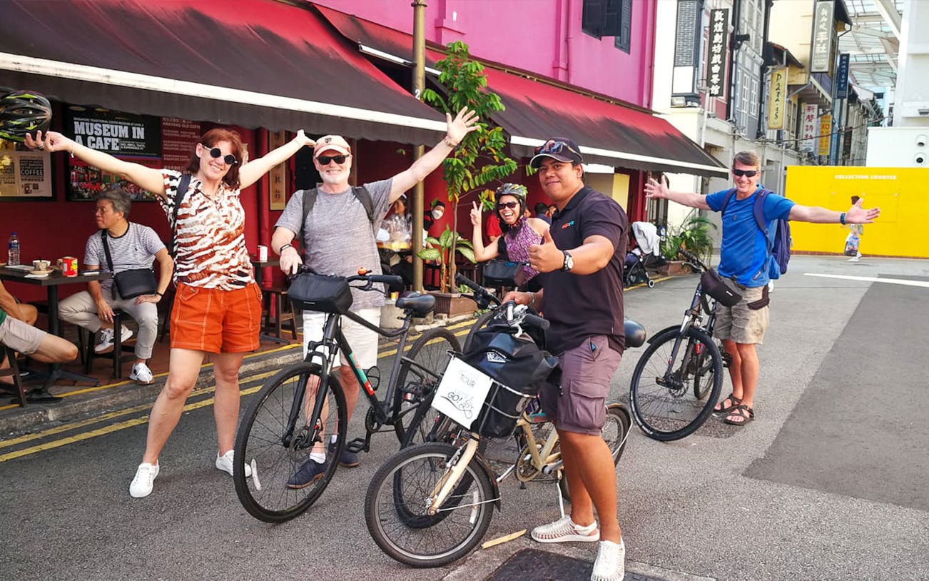 Group of cyclists enjoying a food tour in Singapore, stopping outside a cafe.