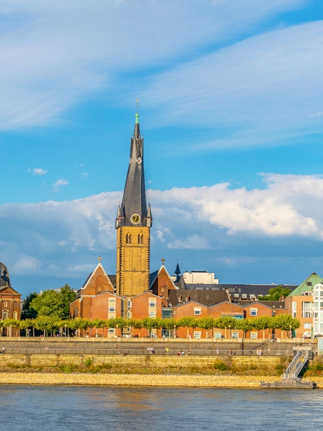 Riverside view of Düsseldorf with historic buildings and church spire on Panorama City Cruise.