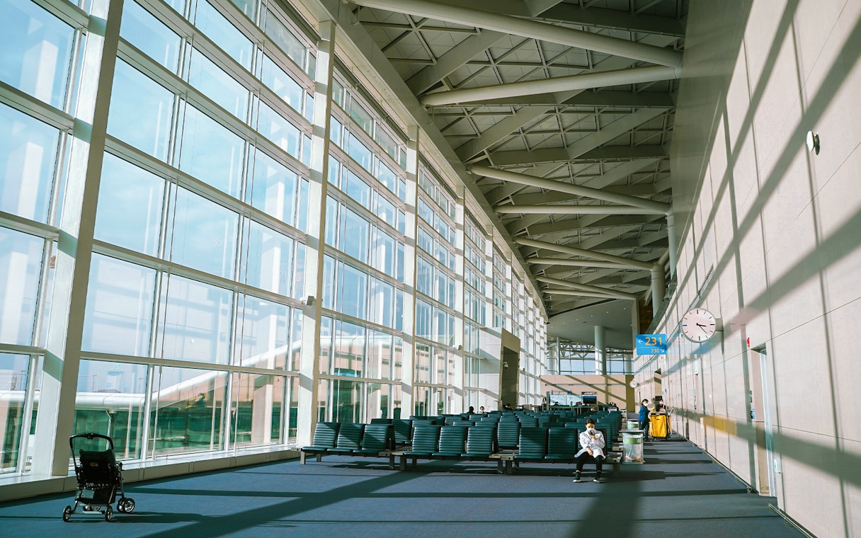 Incheon Airport terminal seating area with large windows and travelers.
