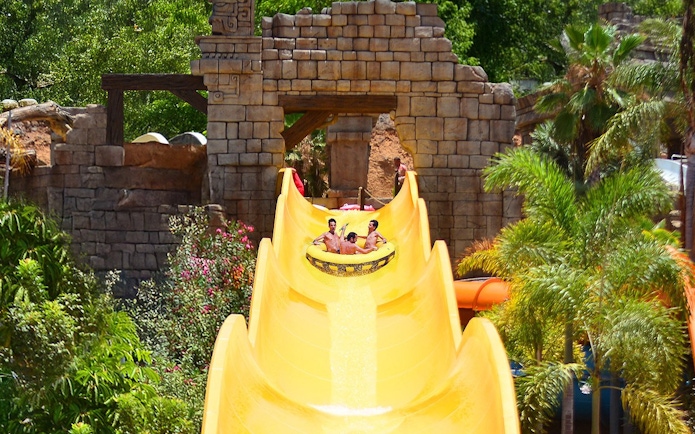 Visitors enjoying Banzai water slide at Aqualand Maspalomas, surrounded by tropical plants.