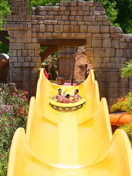 Visitors enjoying Banzai water slide at Aqualand Maspalomas, surrounded by tropical plants.
