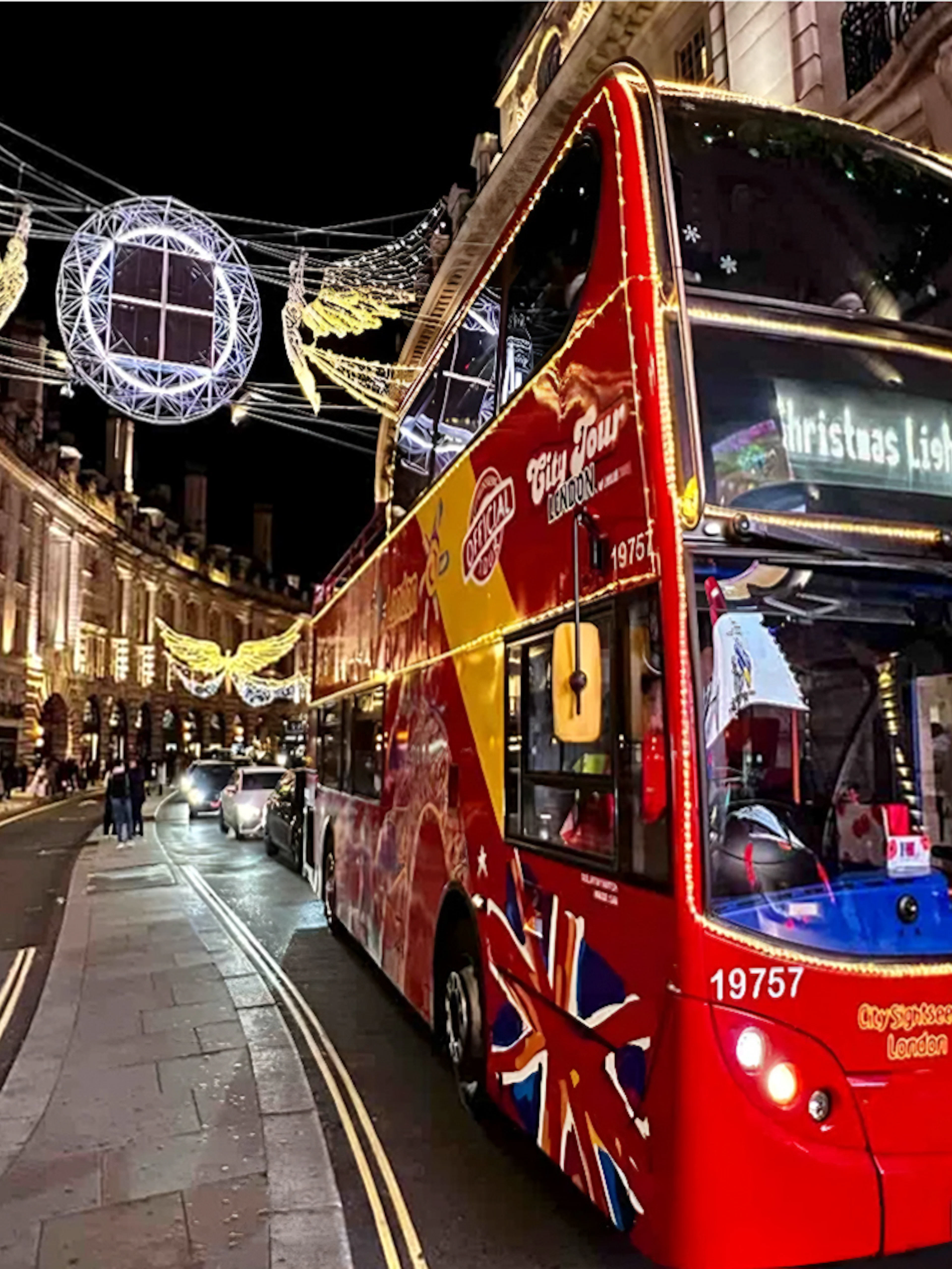 Red double-decker bus on London Christmas Lights Tour under festive street decorations.
