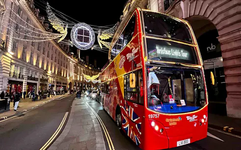 Red double-decker bus on London Christmas Lights Tour under festive street decorations.