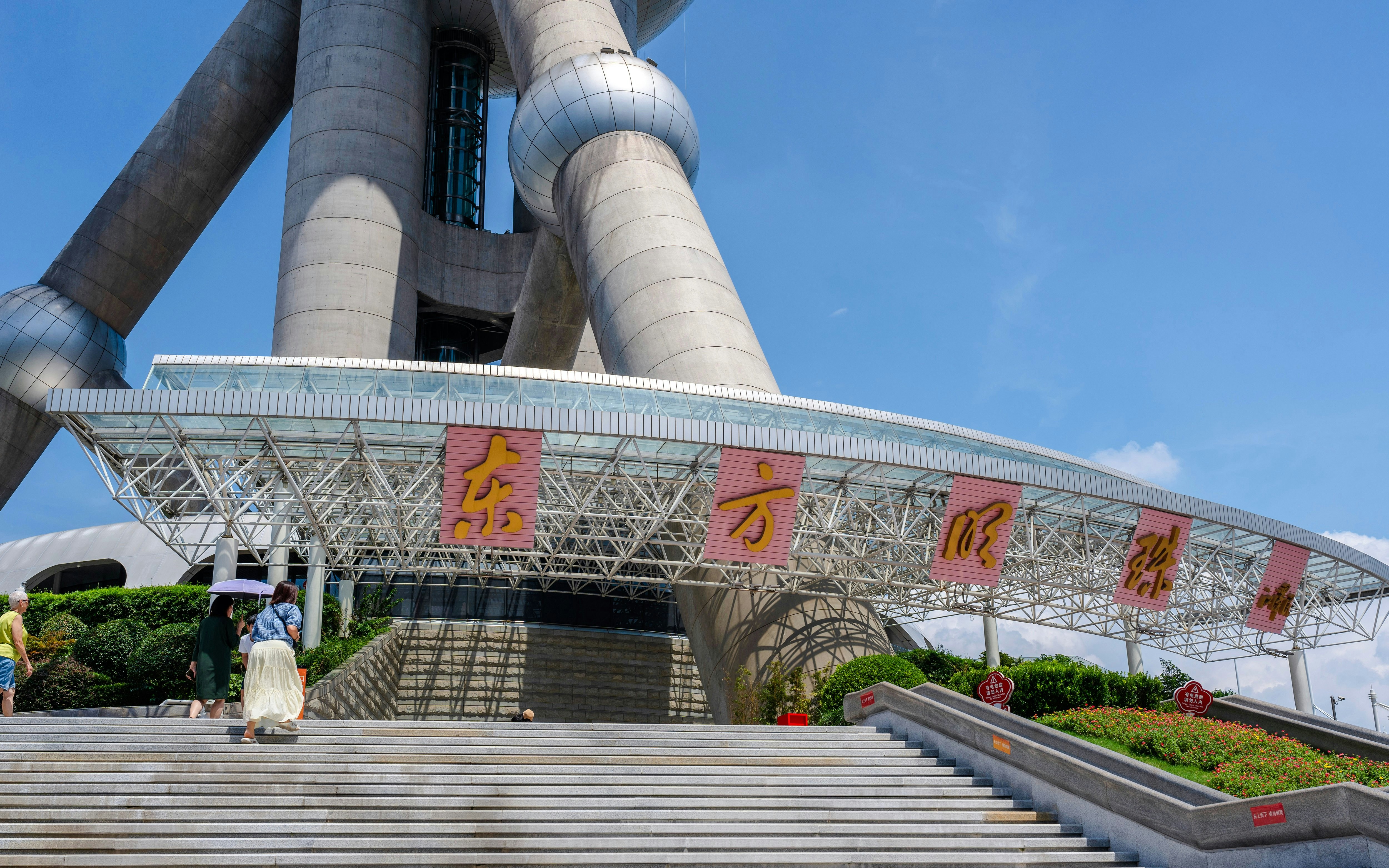 Entrance of Oriental Pearl Tower, Shanghai with visitors on steps.