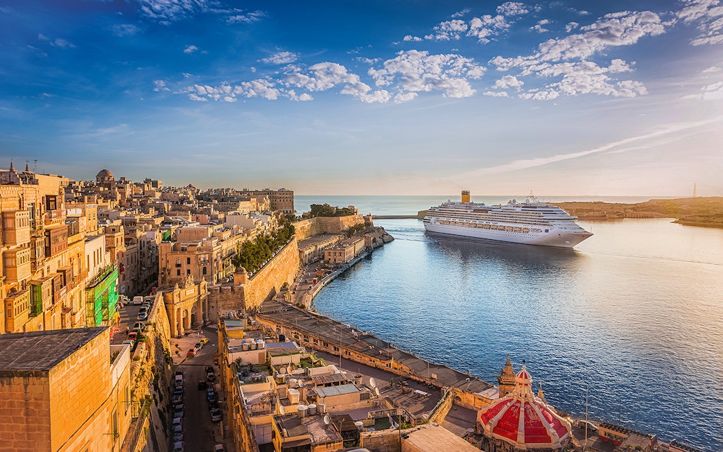 Cruise ship in Valletta harbor with historic cityscape, viewed from Sliema.