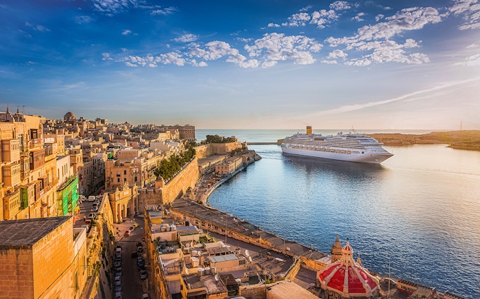 Cruise ship in Valletta harbor with historic cityscape, viewed from Sliema.