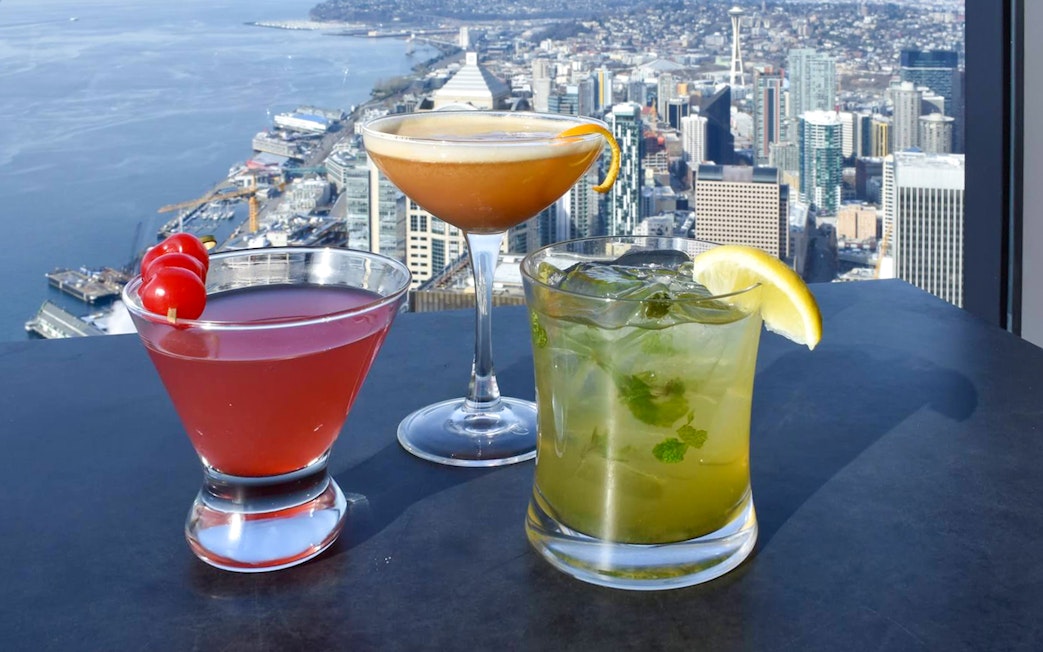 Cocktails on a table with a view of Seattle skyline from Sky View Cafe.
