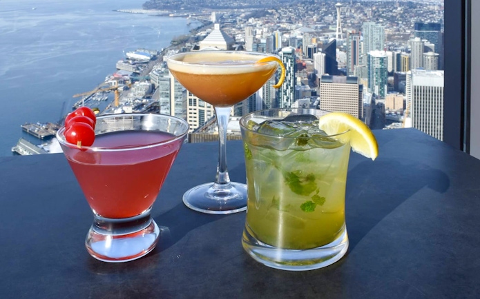 Cocktails on a table with a view of Seattle skyline from Sky View Cafe.