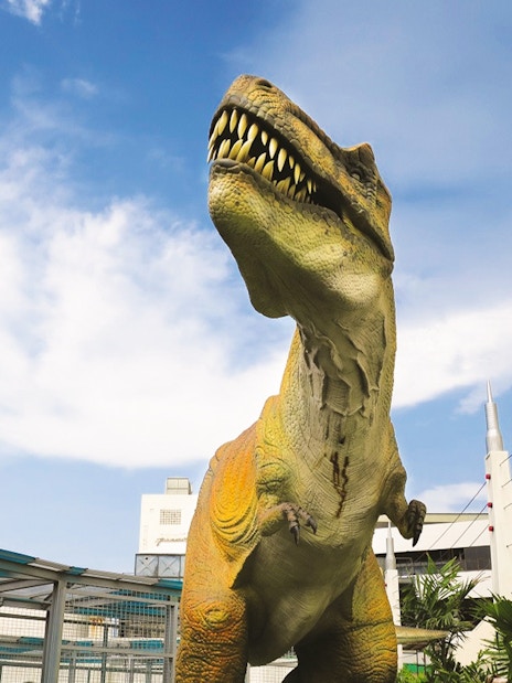 Dinosaur statue at Jurassic Research Centre with buildings in the background.