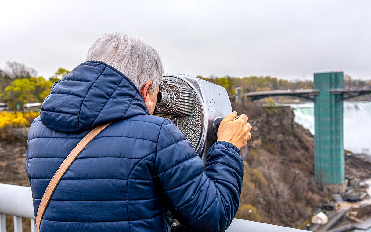 Person viewing Niagara Falls through binoculars on Maid of the Mist tour.