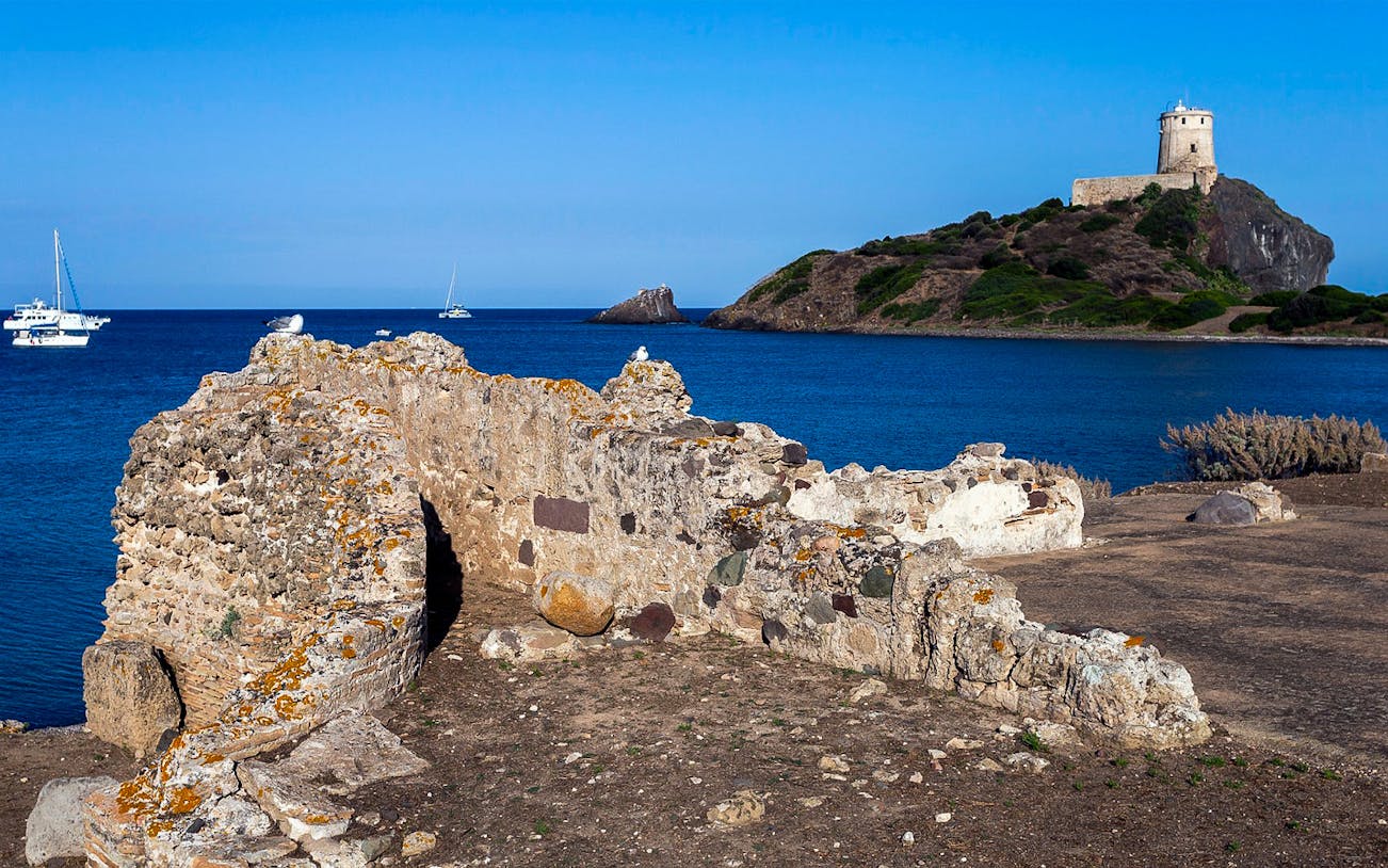 Nora Archaeological Site ruins with coastal view and tower in Sardinia.