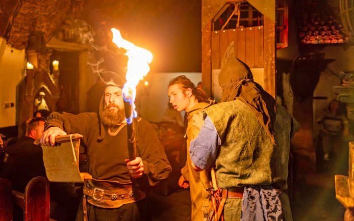 Medieval performers with torch at Dětenice Brewery dinner show near Prague.