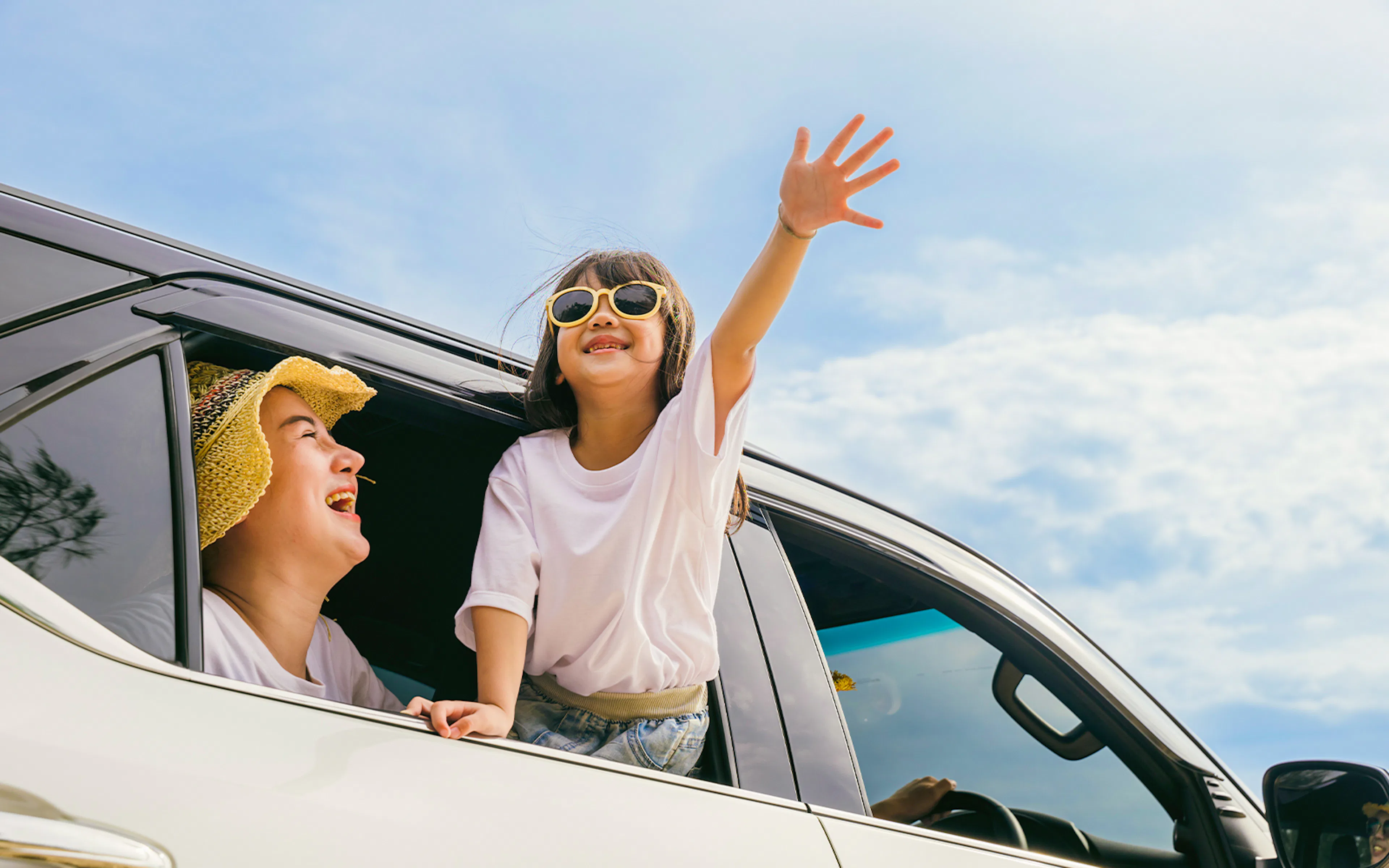 Family enjoying private car transfer with child leaning out window.