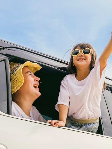 Family enjoying private car transfer with child leaning out window.