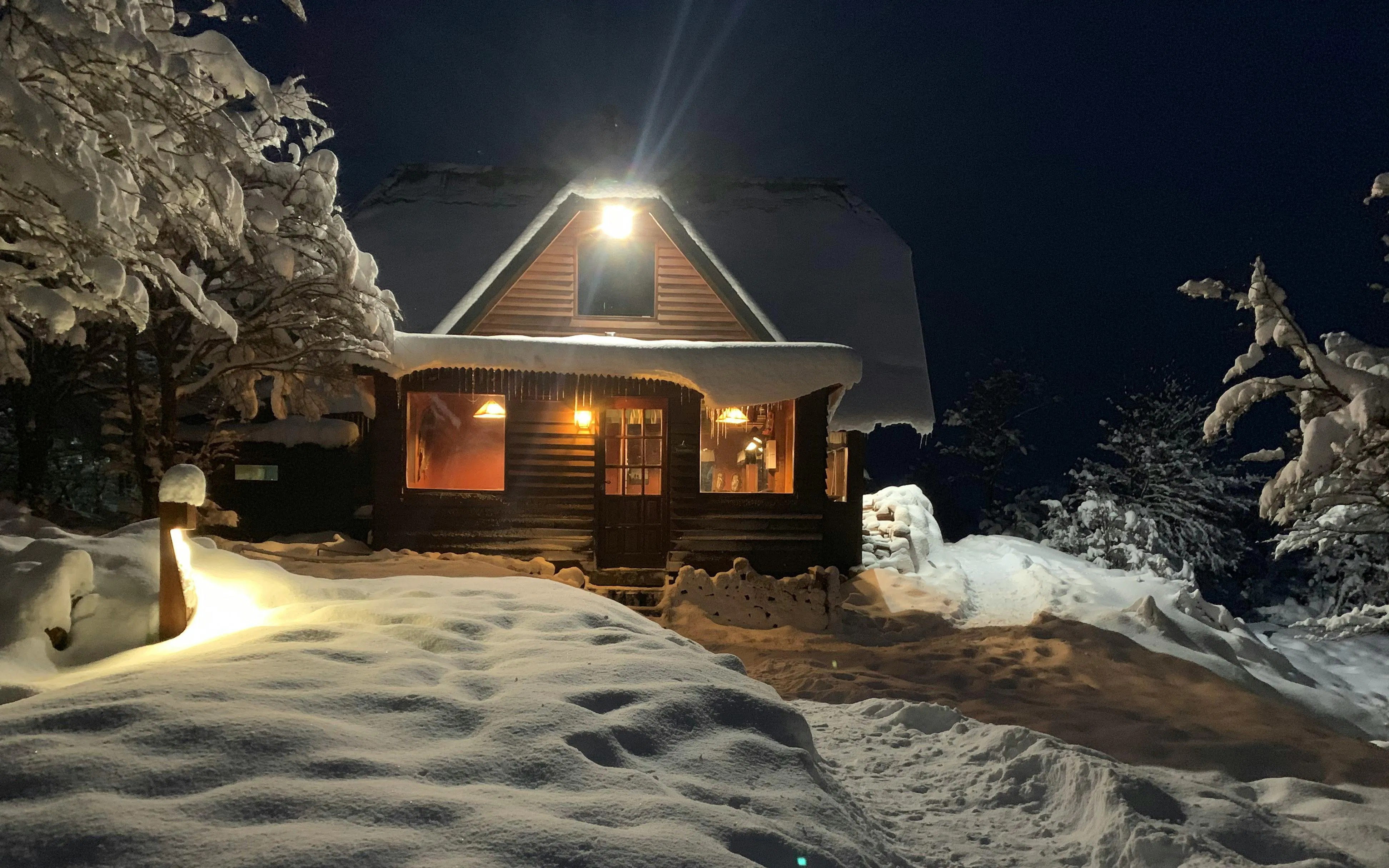 Snow-covered cabin illuminated at night for Snow and Fire Night experience.