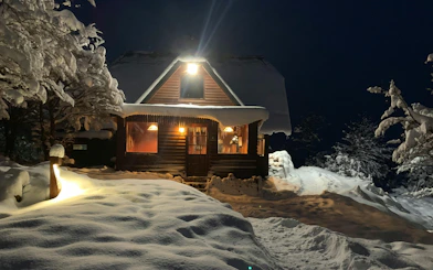 Snow-covered cabin illuminated at night for Snow and Fire Night experience.