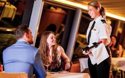 Couple dining on Sydney Harbour cruise with server presenting wine.