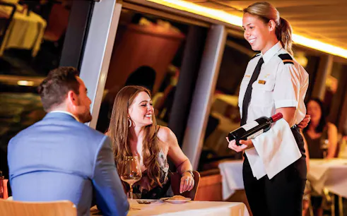 Couple dining on Sydney Harbour cruise with server presenting wine.