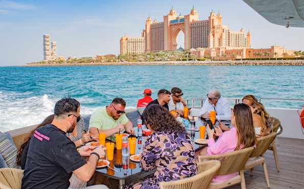 Tourists dining on a Superyacht TriDeck Cruise with Atlantis The Palm in the background, Dubai.