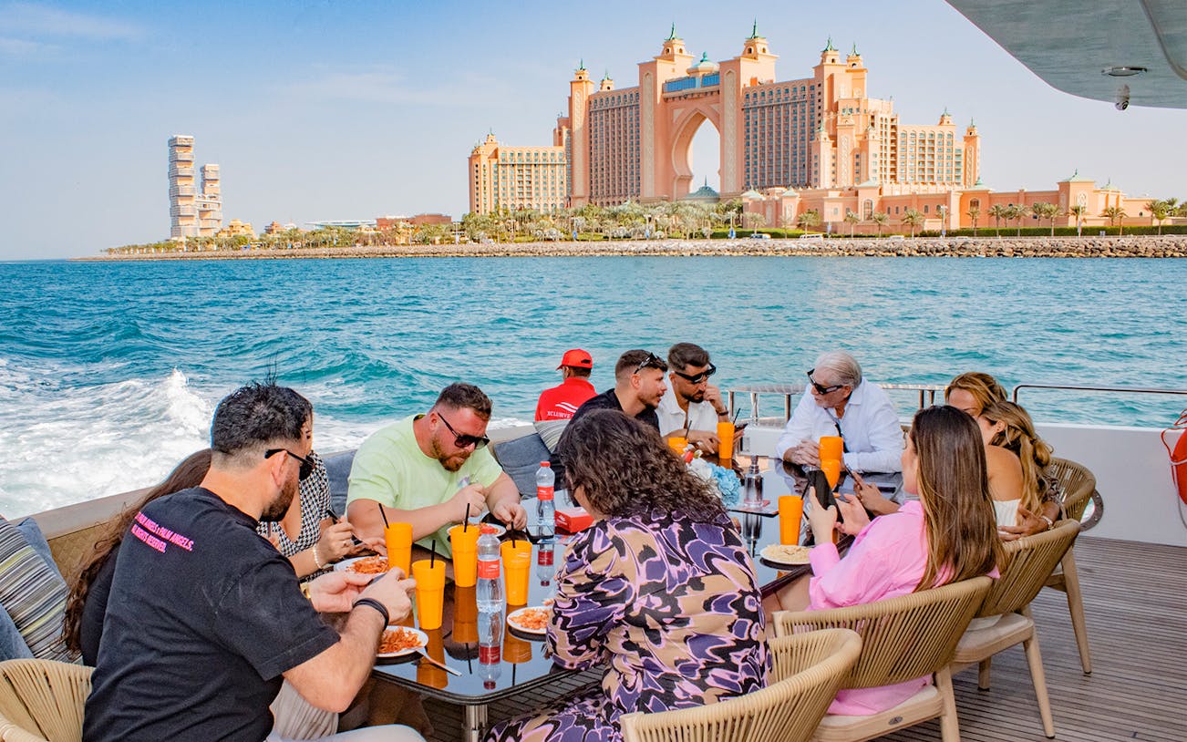 Tourists dining on a Superyacht TriDeck Cruise with Atlantis The Palm in the background, Dubai.
