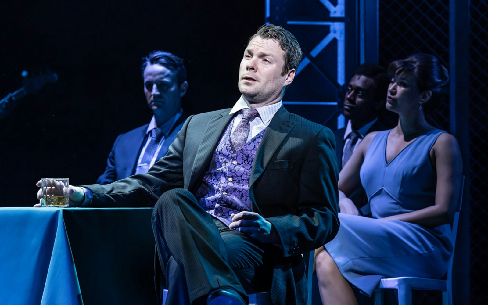 Man in suit holding drink during Jersey Boys performance.