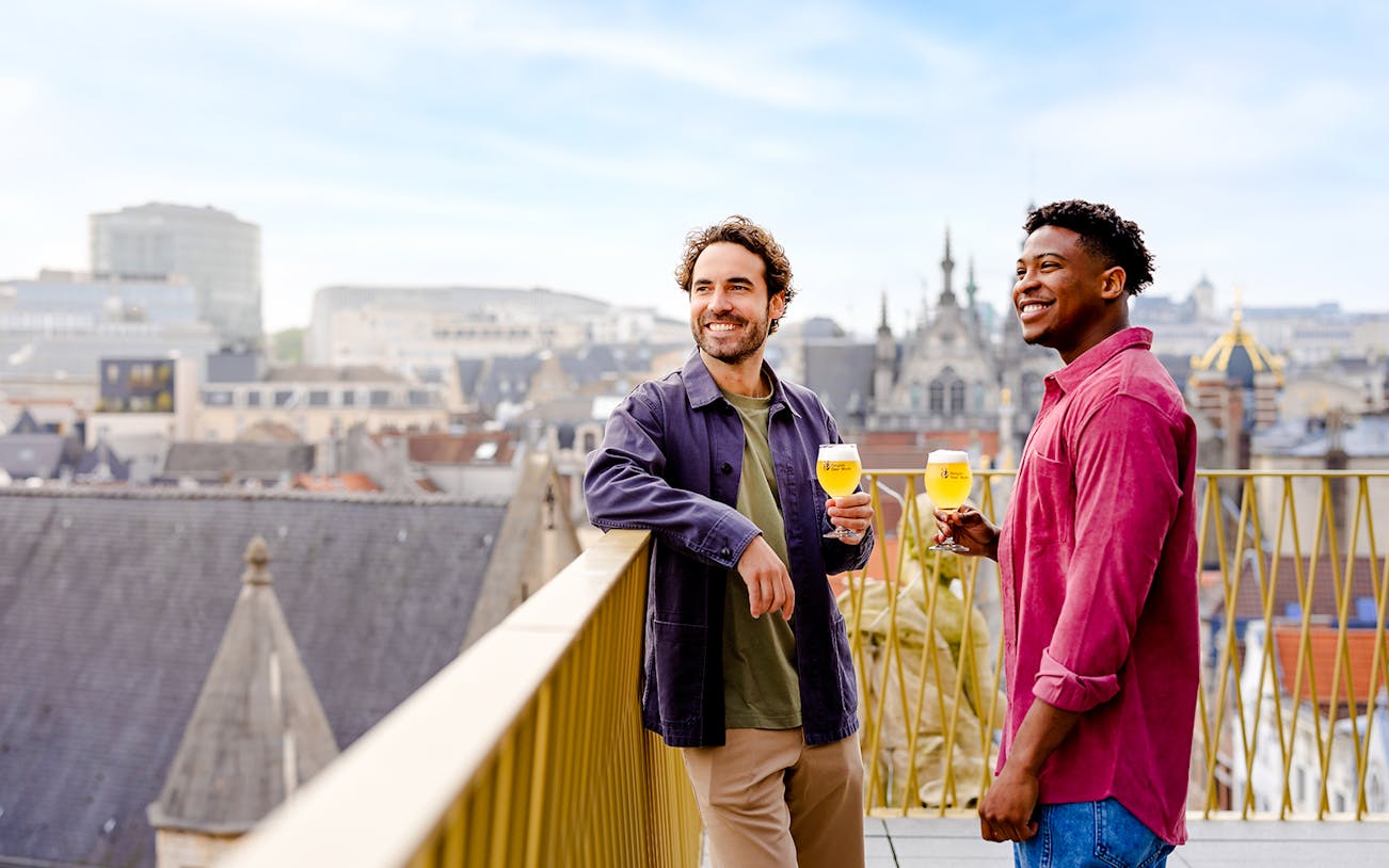 Guests enjoying Belgian beer on a rooftop with Brussels skyline in the background.