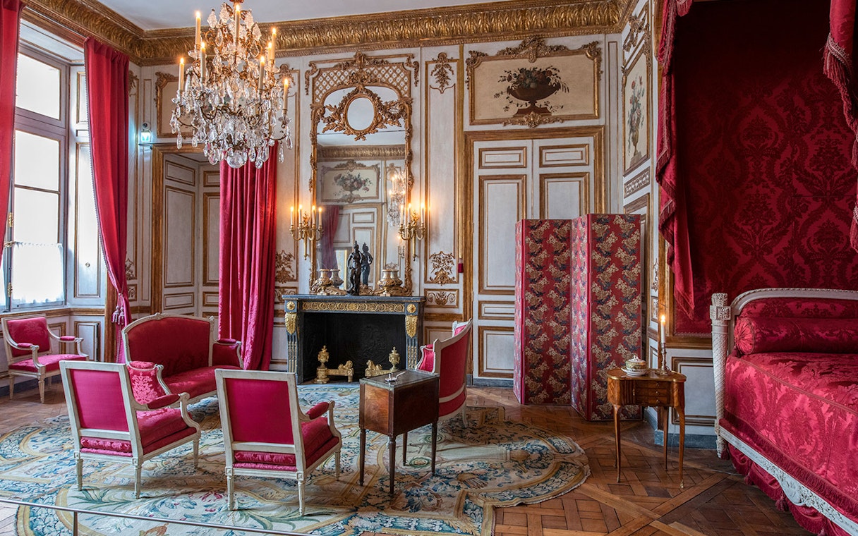 Elegant room with red furnishings and chandelier at Hôtel de la Marine, Paris.