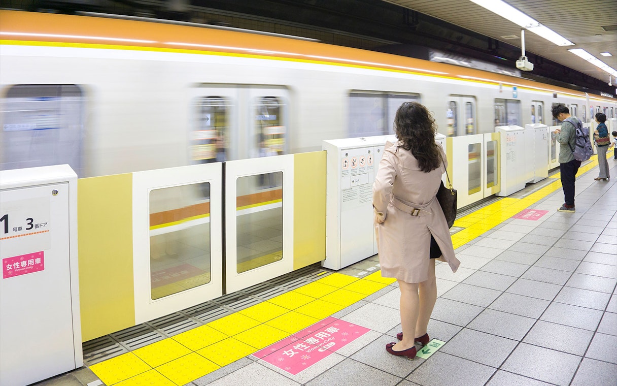 Tokyo subway platform with passengers waiting for a train.