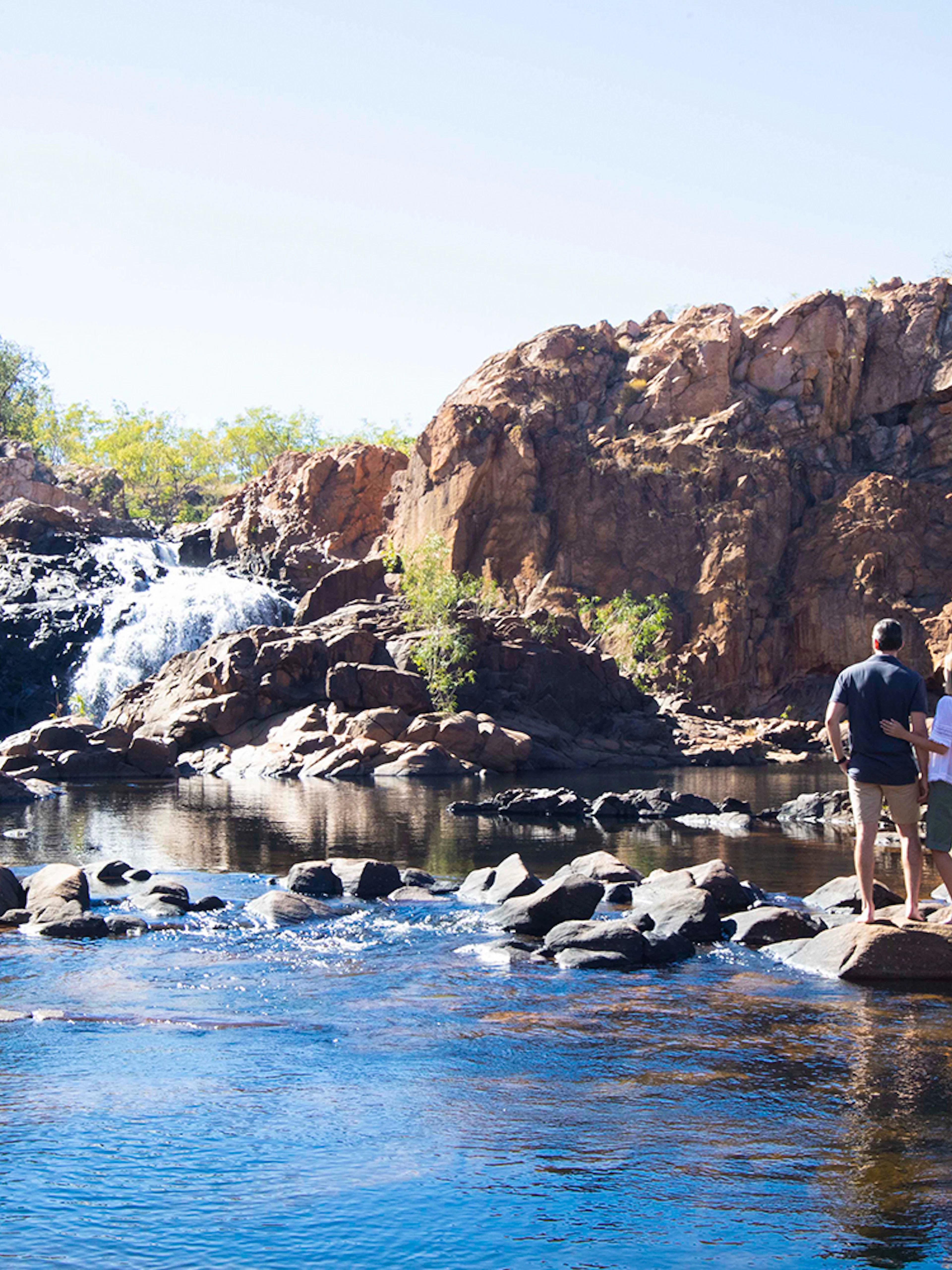 Visitors exploring Katherine Gorge with waterfall and rocky landscape.