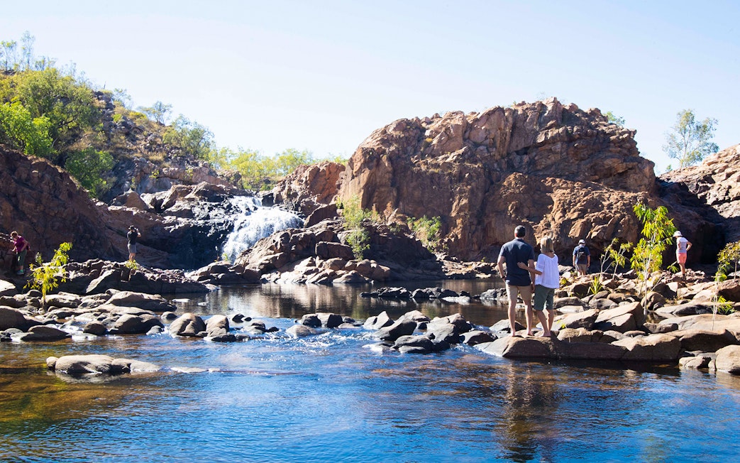 Visitors exploring Katherine Gorge with waterfall and rocky landscape.