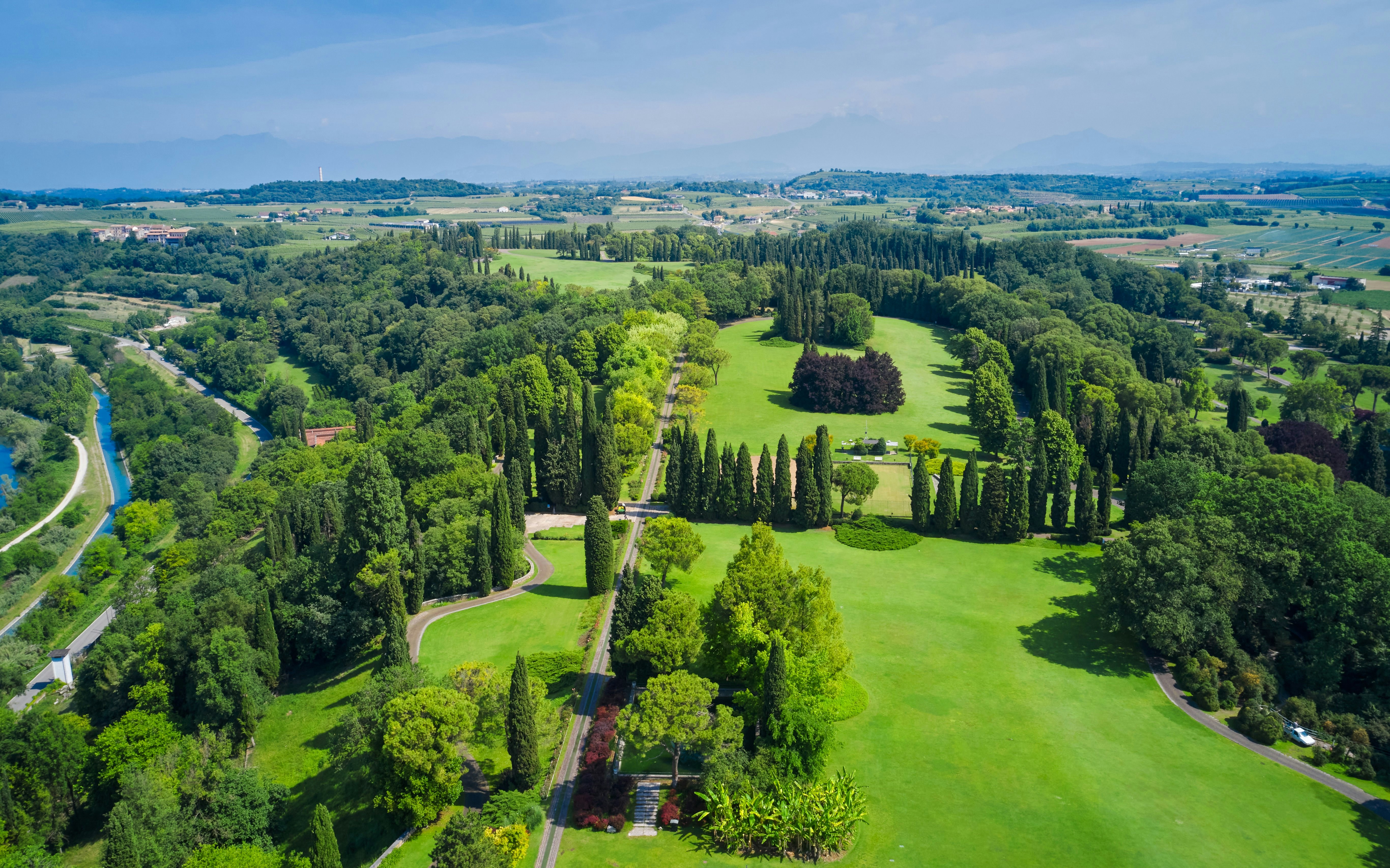 Aerial view of Sigurta Park's lush green landscape and tree-lined paths in Italy.