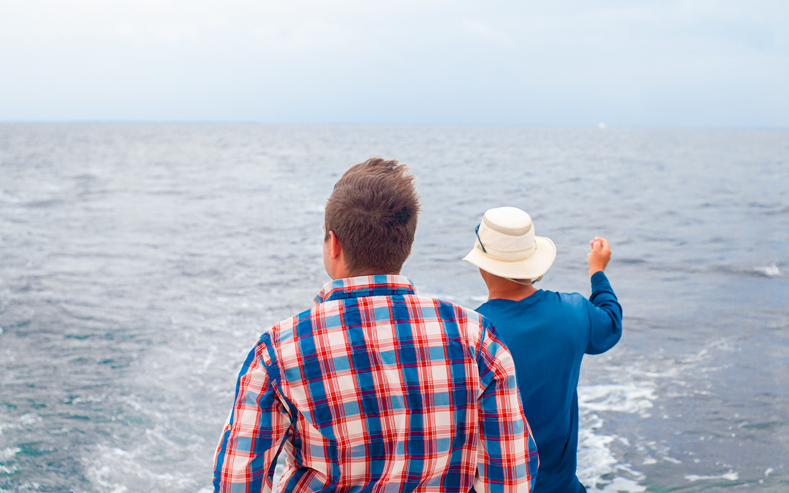 Tourist and guide on a boat in Tenerife, facing the ocean.