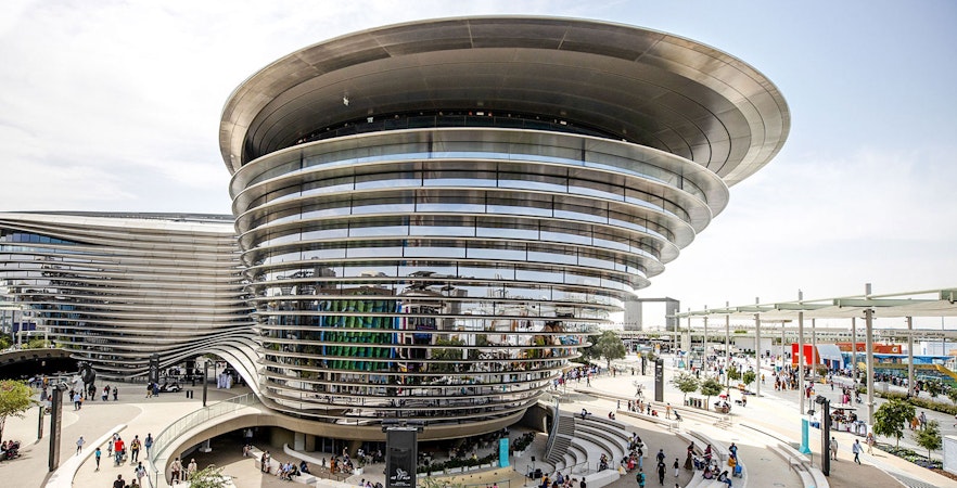 Aerial view of Expo City Dubai entrance with modern architecture and visitors.