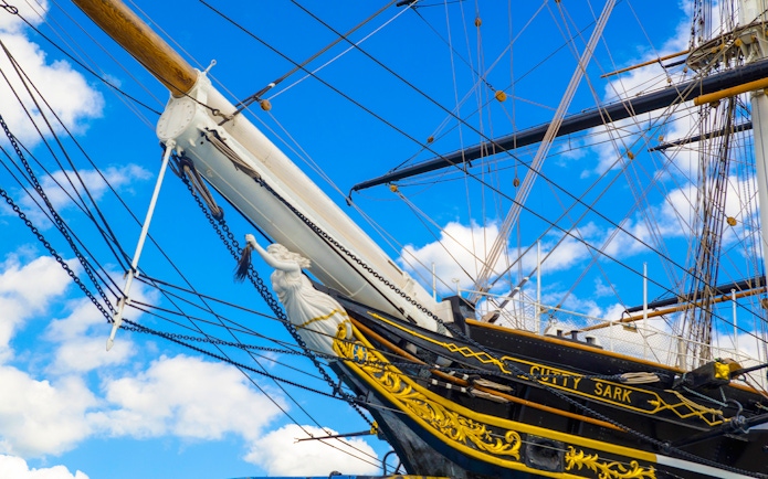 Cutty Sark ship's bow and figurehead against a blue sky in Greenwich.
