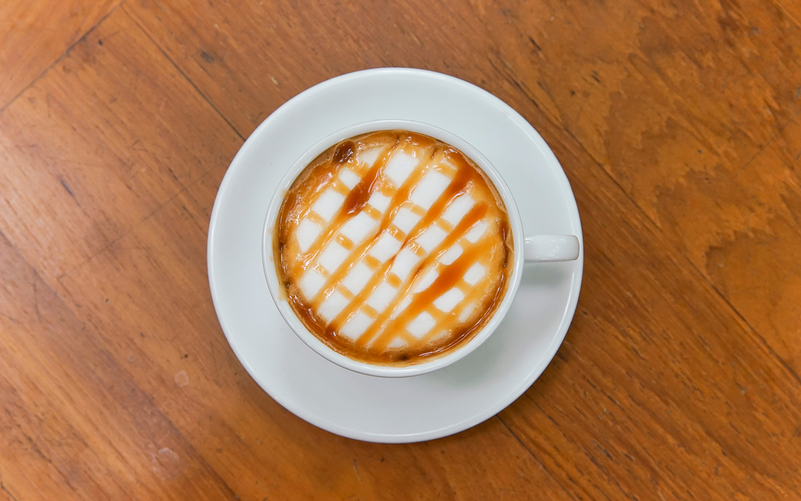 Hot caramel macchiato on wooden table.