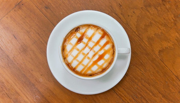 Hot caramel macchiato on wooden table.