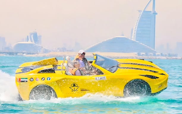 Couple riding jet car in Dubai with Burj Al Arab in background