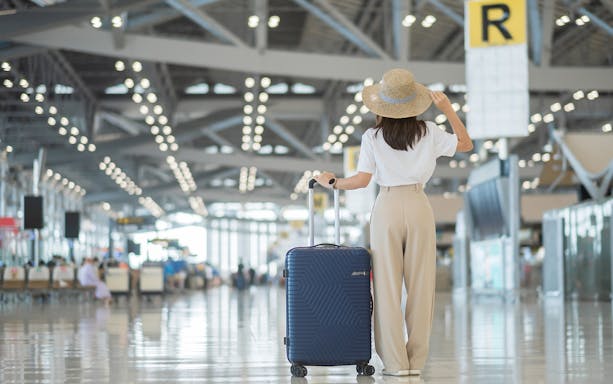 Traveler with suitcase at Bangkok airport terminal.